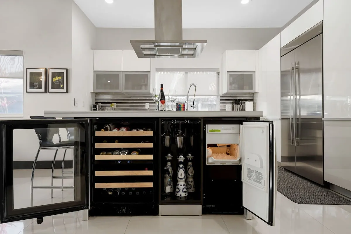 This image features a modern kitchen with a prominent kitchen island, wine cooler, and a suite of modern appliances. The open layout provides plenty of space for multiple people to move around, highlighting the kitchen’s role as a social hub. The clean lines and inviting atmosphere set the stage for group meal preparation and gatherings.